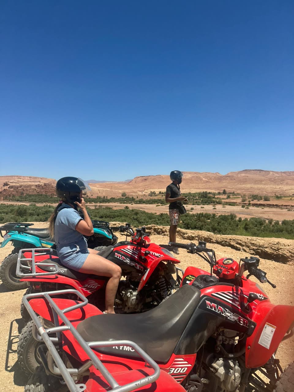 Riders on red quads overlooking the oasis valley
